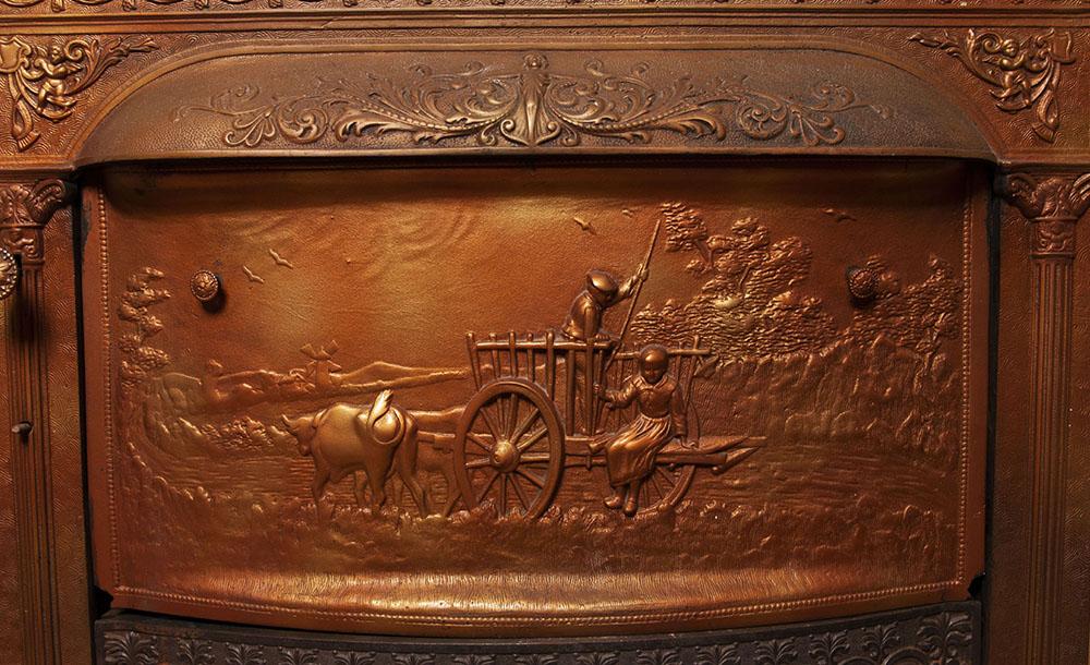 A photo of an elaborate cast copper pictorial firebox closure inside the Gaunt House.